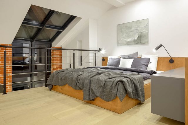 Modern bedroom on mezzanine in loft style apartment with big window and brick wall tipe apartemen di pasar properti Indonesia