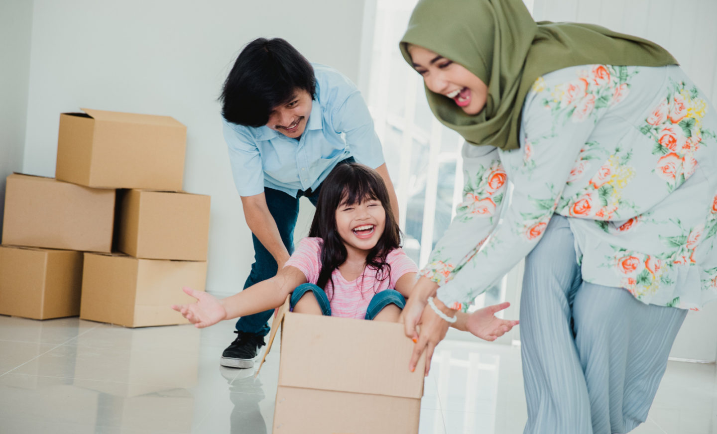 Happy asian family enjoying their new home together. playing with cardboard box