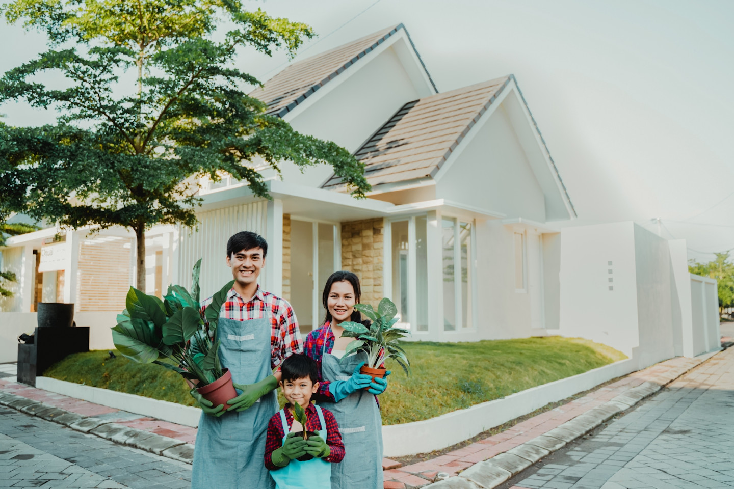family gardening concept. asian parent with son holding a pot of plant and smiling to camera together